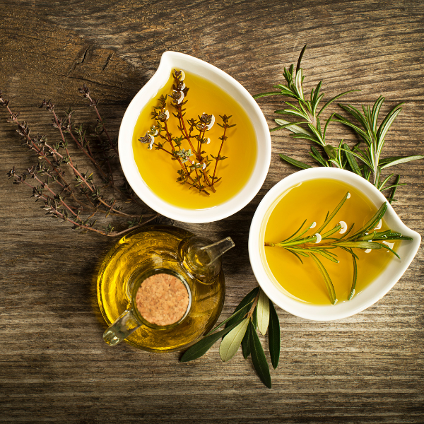 An oil pourer and two bowls of olive oil with herbs